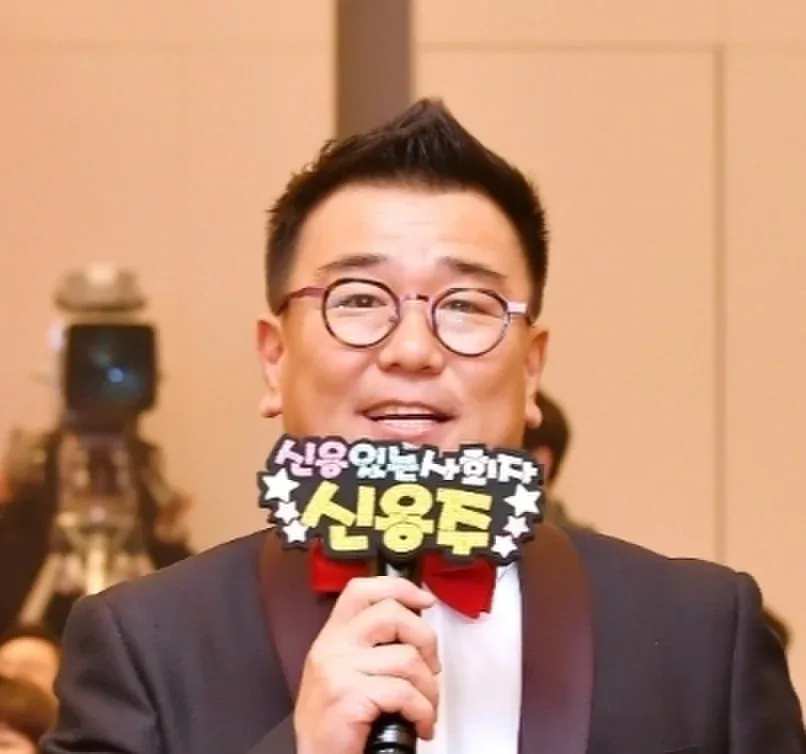 마이크를 들고 객석을 향해 말하는 신용주 MC의 근접 모습