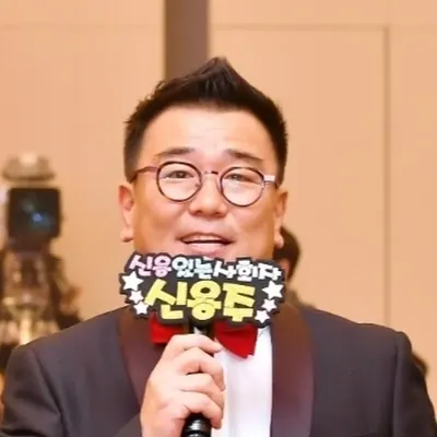 마이크를 들고 객석을 향해 말하는 신용주 MC의 근접 모습