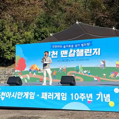 야외 행사장 무대 위에서 진행하는 사회자와 현수막