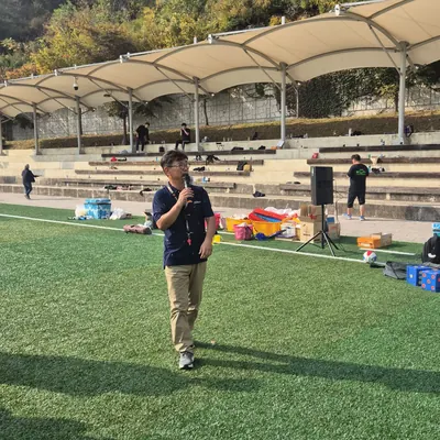운동장에서 게임 방법을 안내하는 진행자와 참가자들