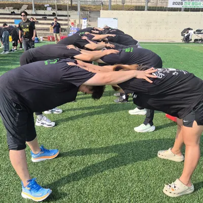 야외 운동장에서 진행자의 안내에 따라 팀 게임을 하는 참가자들