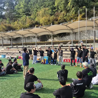 야외 운동장에서 진행자의 안내에 따라 팀 게임을 하는 참가자들