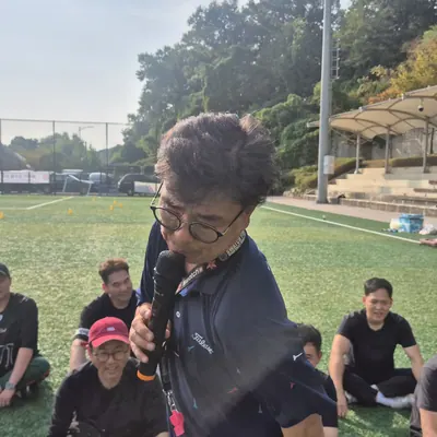 운동장에서 게임 방법을 안내하는 진행자와 참가자들