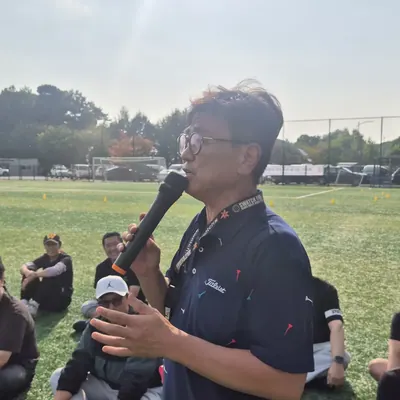 운동장에서 게임 방법을 안내하는 진행자와 참가자들