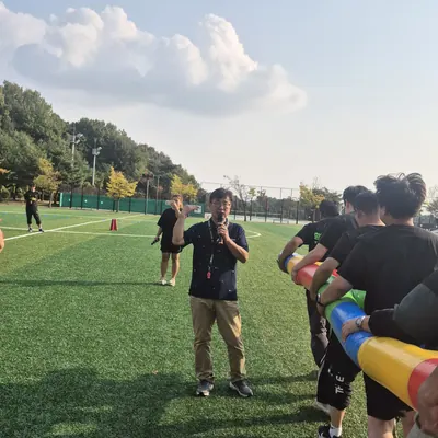 운동장에서 게임 방법을 안내하는 진행자와 참가자들