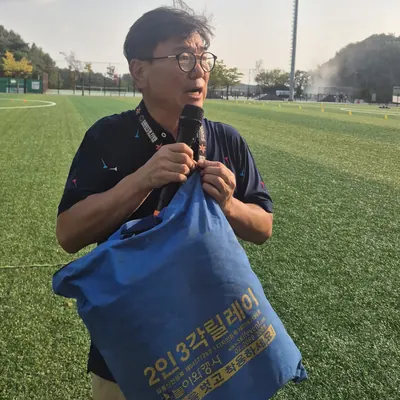 운동장에서 게임 방법을 안내하는 진행자와 참가자들